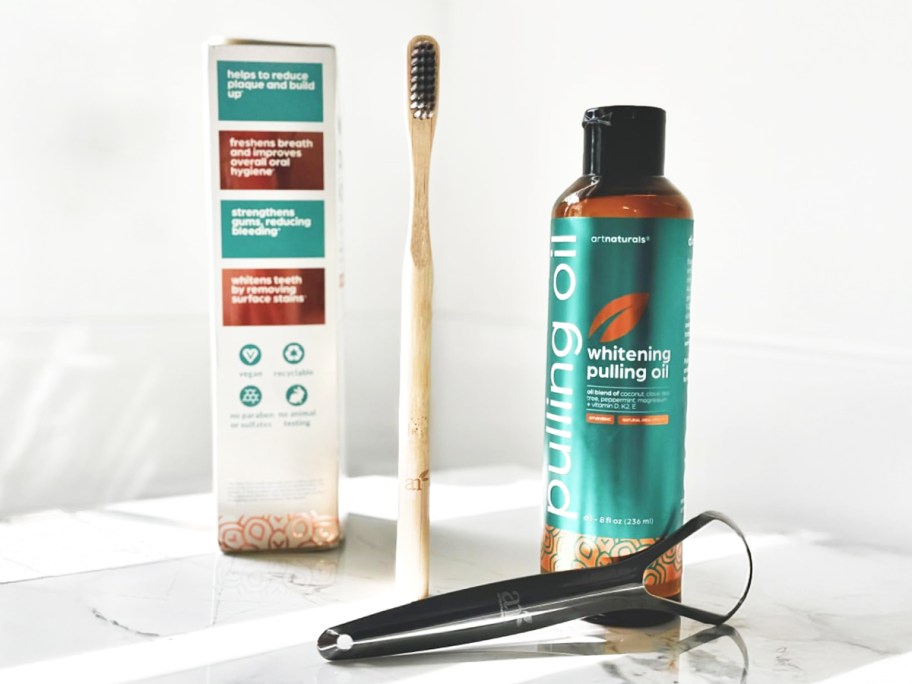 bottle of pulling oil, bamboo toothbrush, and tongue scraper 
