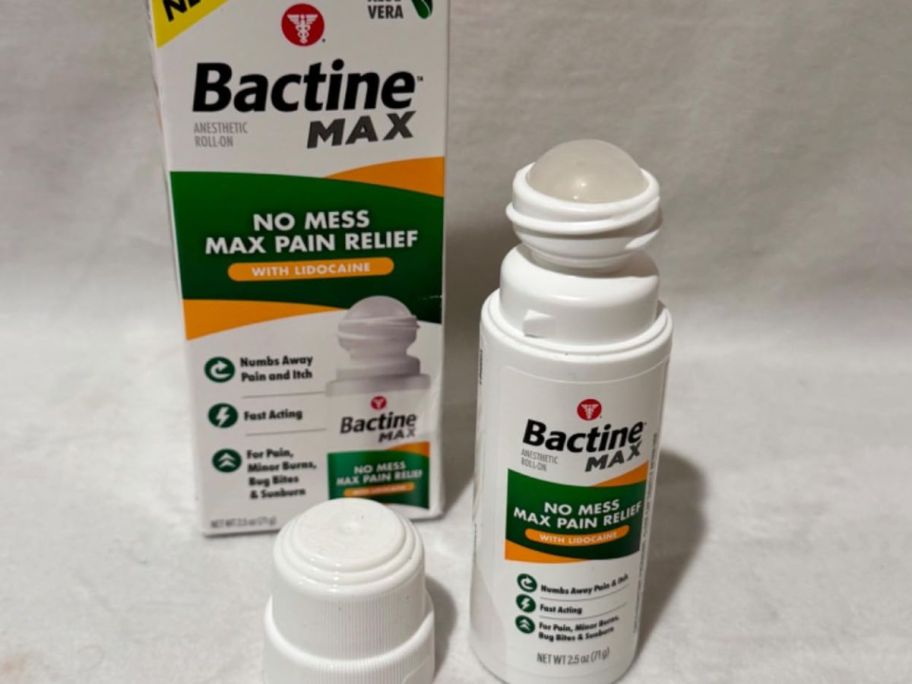 An open roller bottle of Bactine Max next to the packaging it comes in