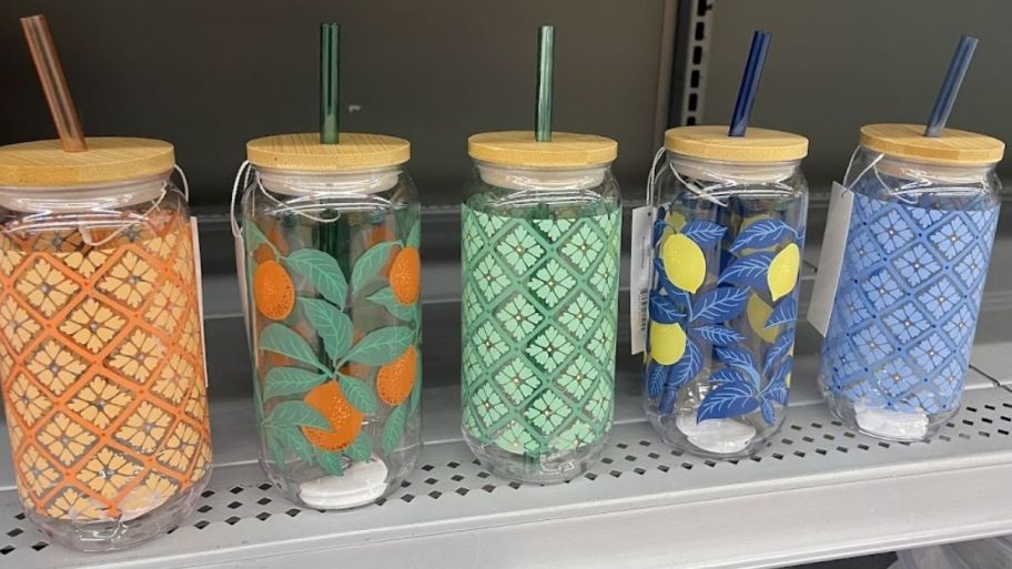 lidded tumblers with straws in various graphic designs on a store shelf