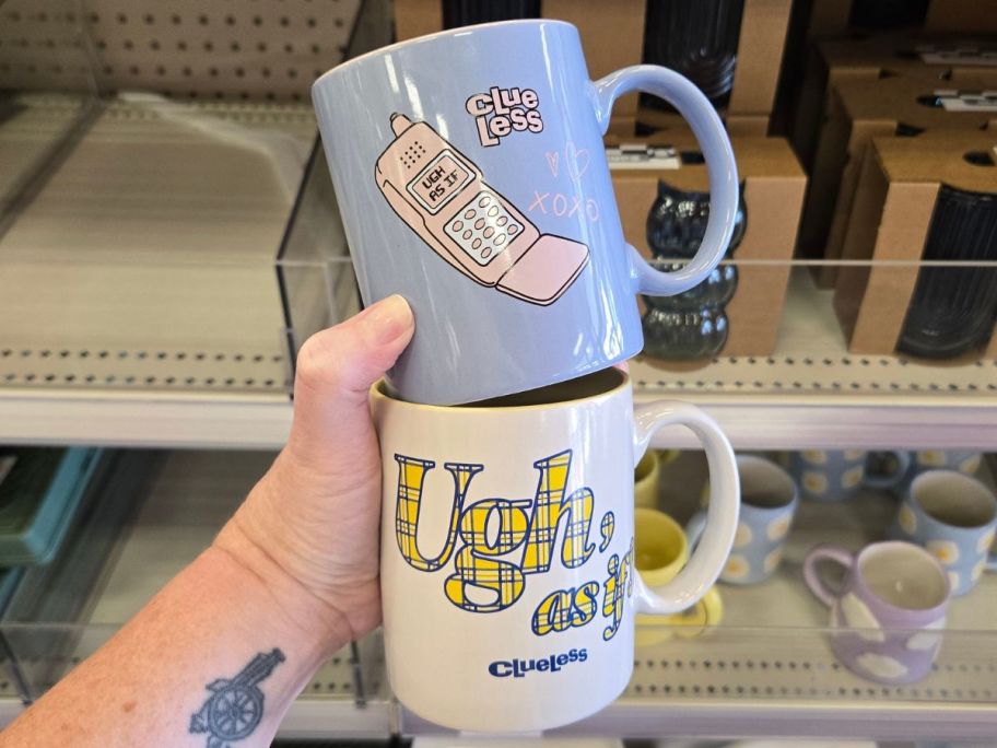 Hand holding two Clueless Themed Coffee Mugs