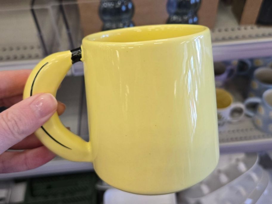 Hand holding a yellow mug with a banana handle