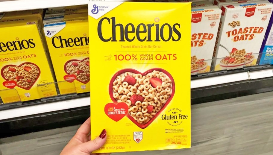 hand holding a yellow box of Cheerios Cereal in store