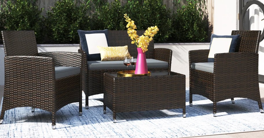 brown wicker chairs and loveseat with dark grey cushions and matching coffee table