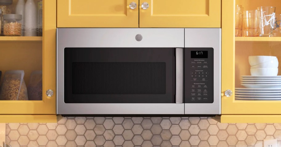 black and stainless steel microwave between yellow cabinets in kitchen