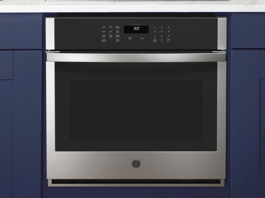 stainless steel and black wall oven between blue kitchen cabinets