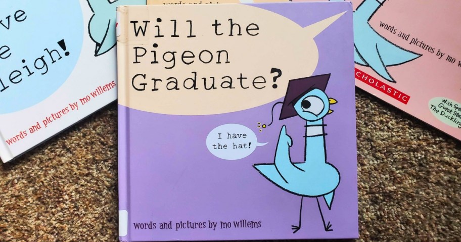a hardcover "Will the Pigeon Graduate?" book by Mo Willems laying next to other Pigeon books