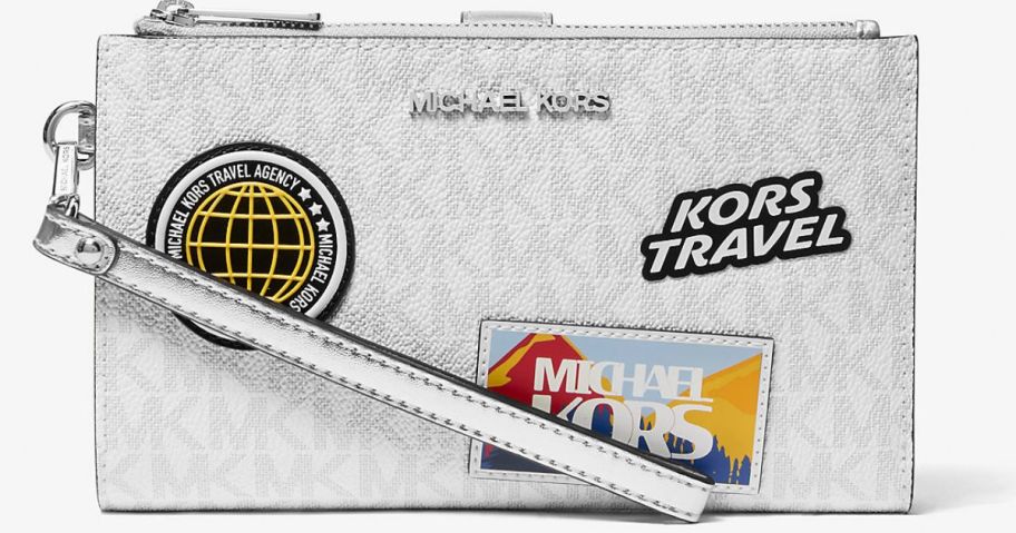 A Michael Kor's wristlet with travel patches on it 