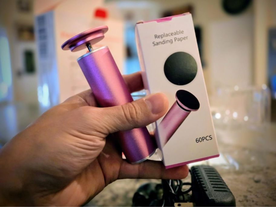 A person holding a pink electric foot file 