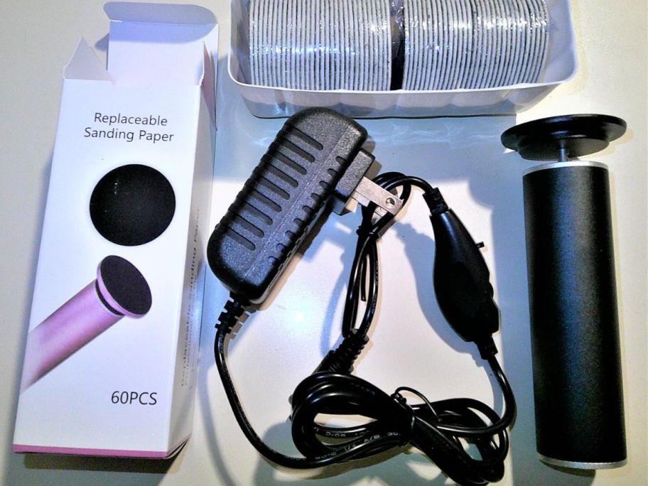 A box containing a black electric foot file, plug, and replacement pads