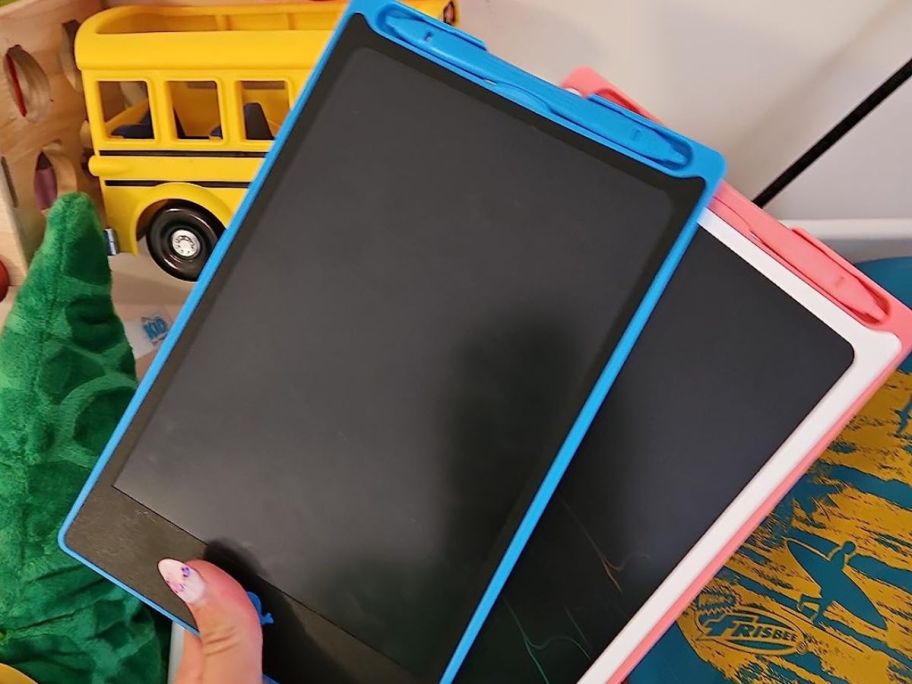 Hand holding two LCD writing tablets