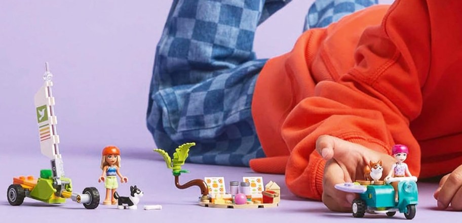 kid laying on floor playing with LEGO Friends Surfing Dogs and Scooter Adventure set