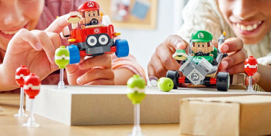 two kids playing with lego mario kart set