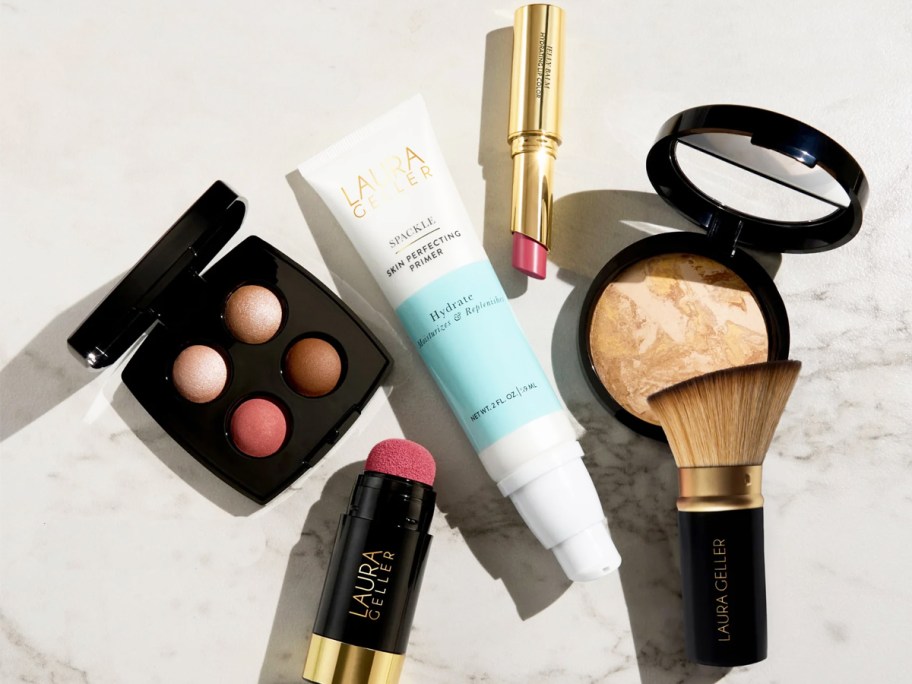 laura geller pressed foundation, lipstick, primer, eyeshadow, blush, and brush on marble table