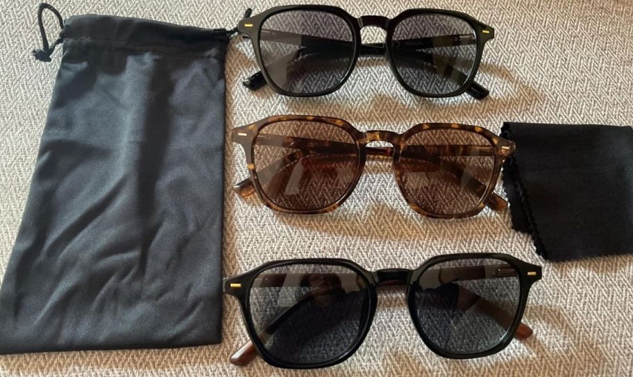 three pair of reading sunglasses shown with cleaning cloth and carry bag