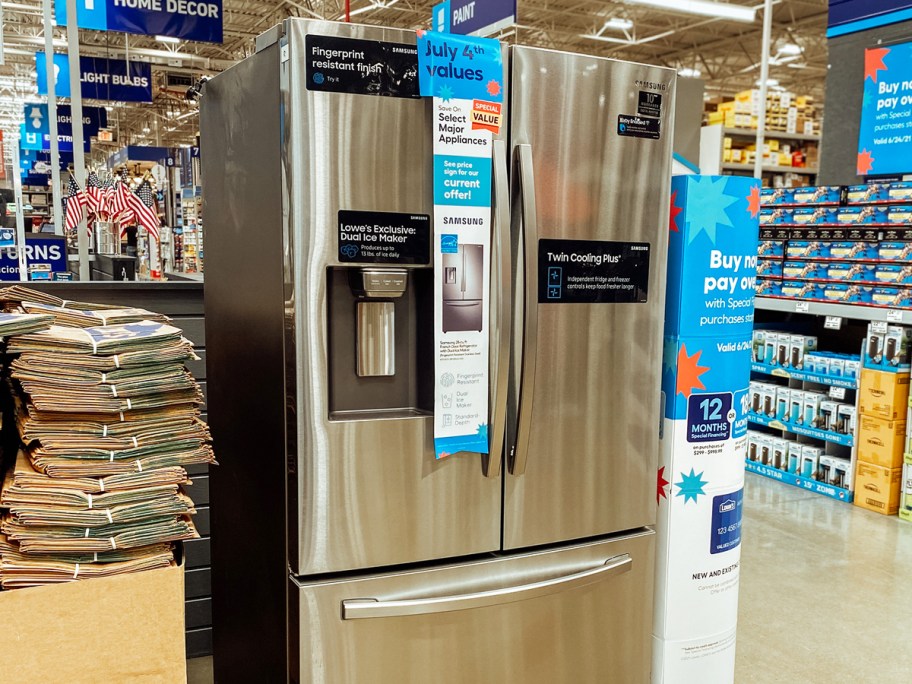 stainless steel fridge on display in store with 4th of july sale tags on it