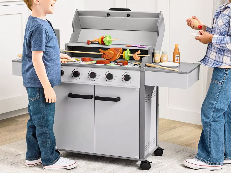 two kids playing with a gas grill playset