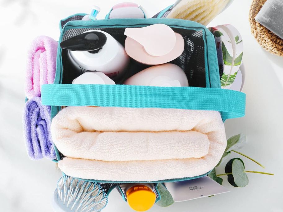 Top down view of a mesh shower caddy with shoer essentials like hair care, body wash, towels, brushes and more