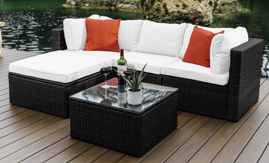 black wicker patio sofa with white cushions and red pillows