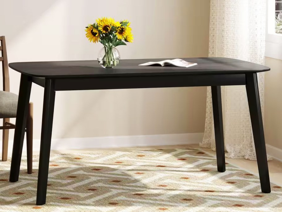 black rectangular dining table with vase of sunflowers on top