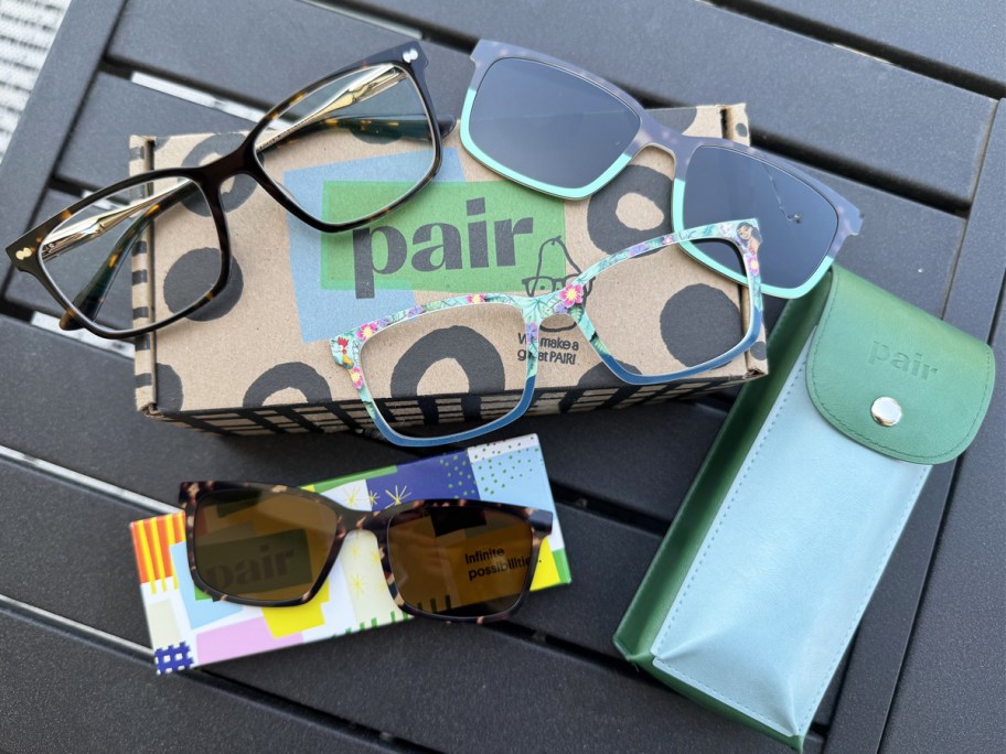 pair of glasses with 3 toppers and case on top of black table