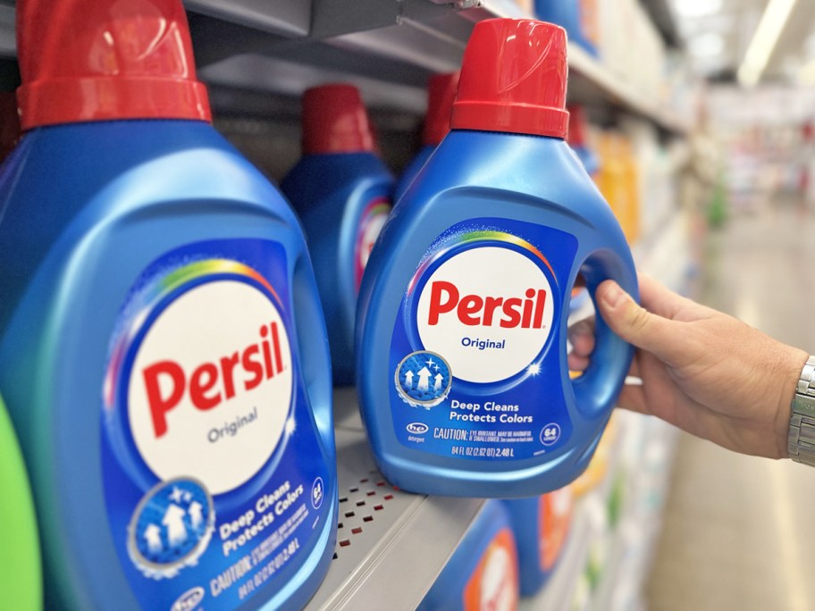 hand grabbing a blue bottle of Persil Deep Clean Liquid Laundry Detergent from store shelf