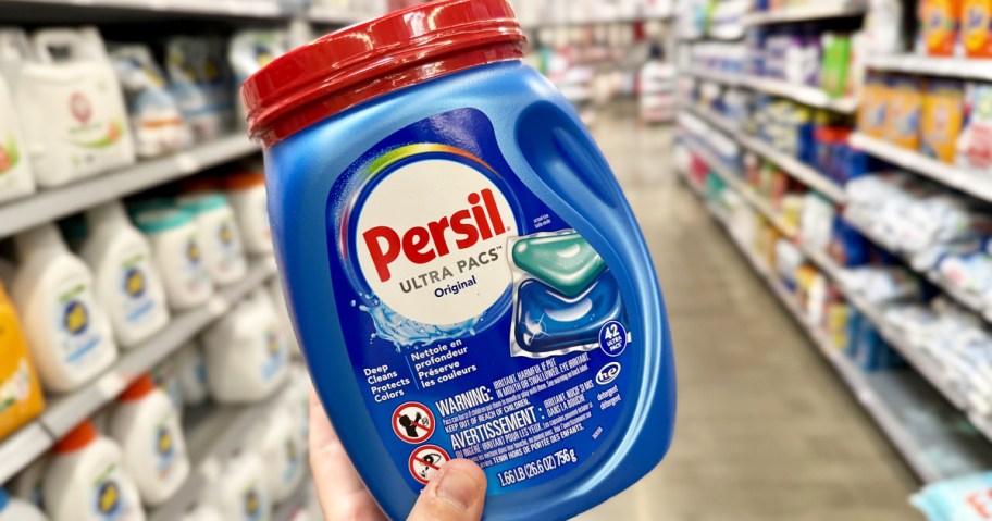 hand holding up a blue container of Persil Laundry Detergent Pacs in store