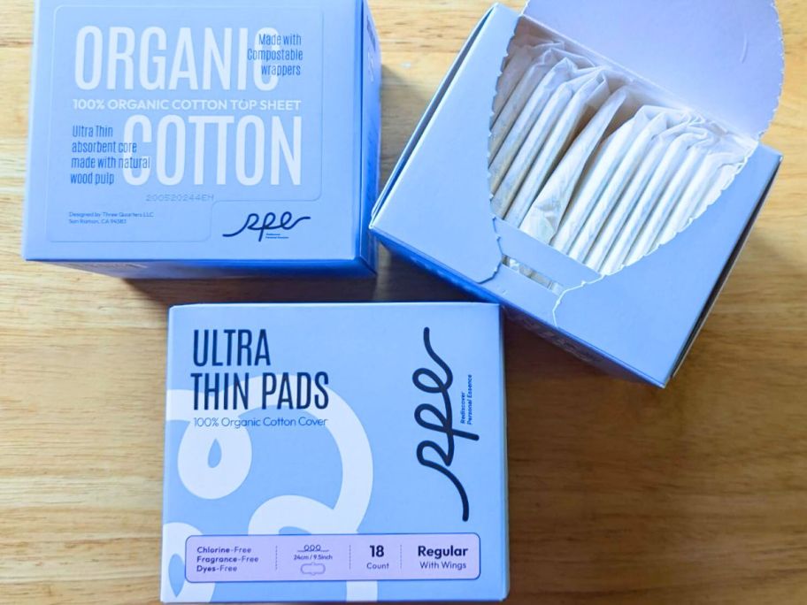 3 boxes of RPE Life Organic Feminine Pads with one open showing thin, wrapped pads inside