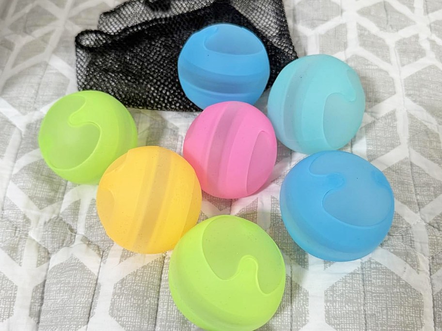 colorful reusable water balloons and mesh bag on a grey blanket