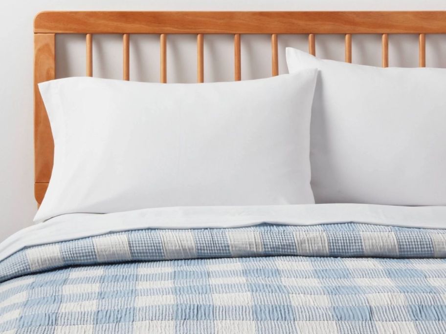 plaid quit light blue on a wooden bedframe