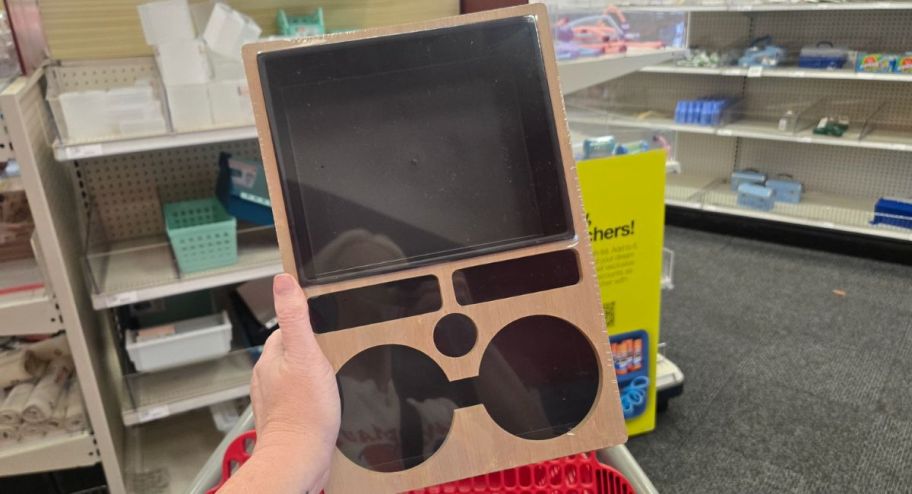hand holding a wooden tray in front of a target cart