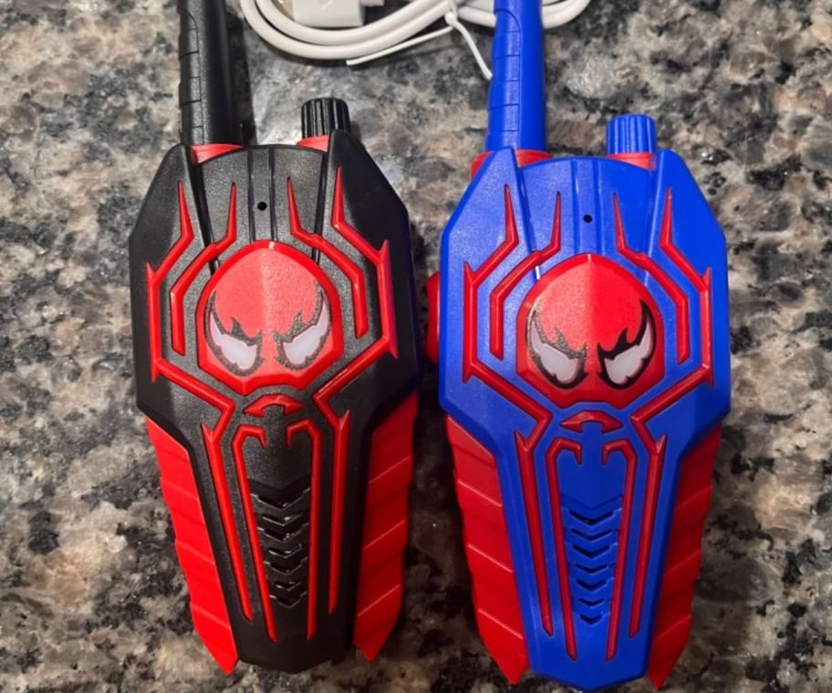 Two kids walkie talkies with a Spiderman-like logo on them