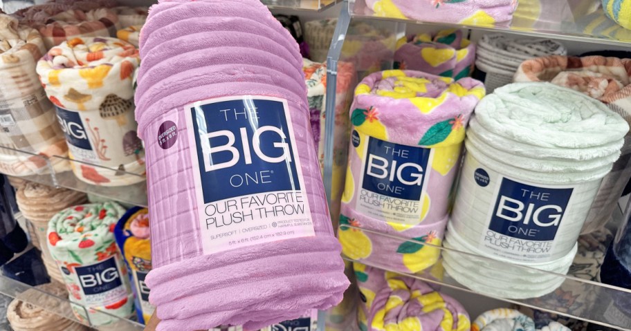 hand holding up purple ribbed throw blanket in store