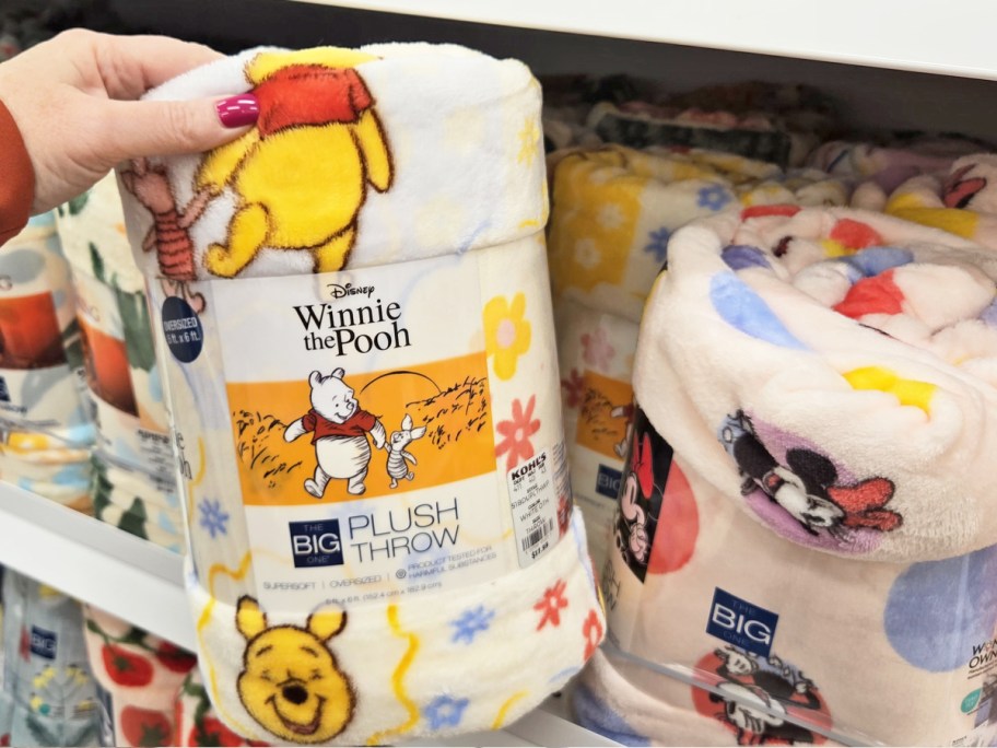 hand grabbing winnie the pooh throw blanket from store shelf