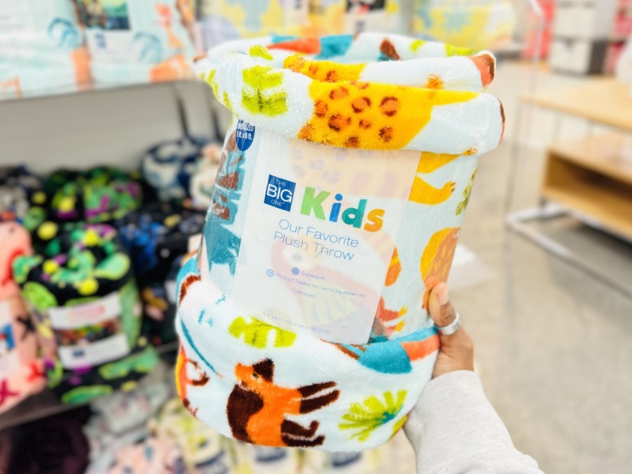 hand holding up an animal print throw blanket in store