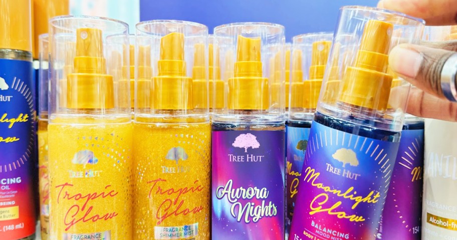 hand grabbing a bottle of Tree Hut Fragrance Mist from store shelf