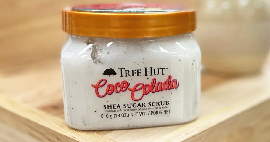 white jar of Tree Hut Shea Sugar Body Scrub on wood table