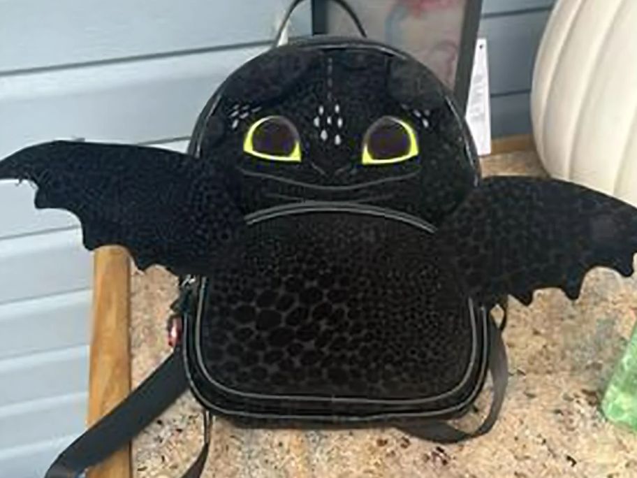 A Toothless the dragon mini backpack with cute extended wings on a table 