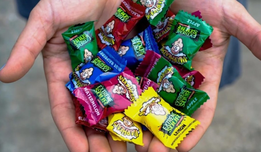 person holding warheads candies in the palms of their hands