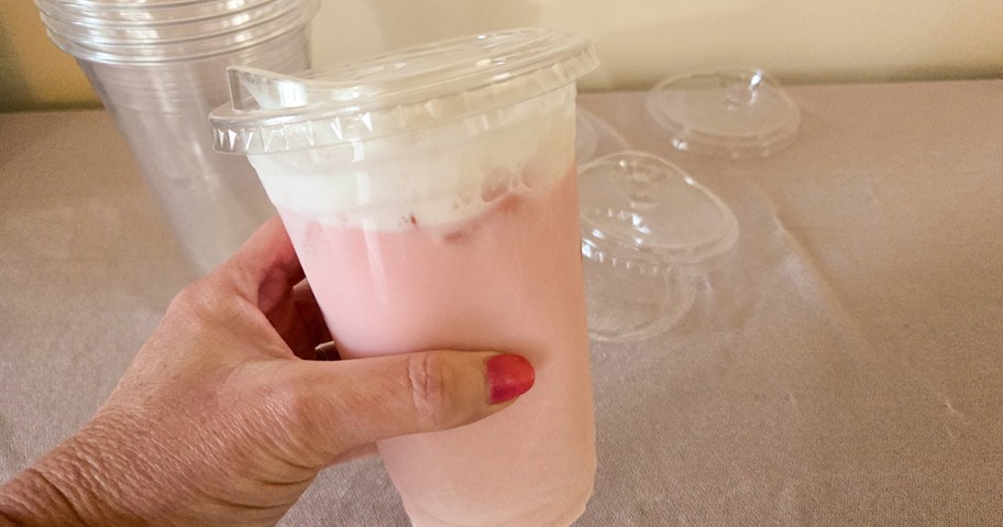 Woman holding plastic cup with pink drink