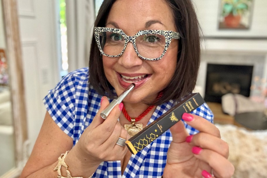 woman applying silver tube of lipstick