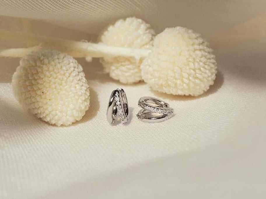silver huggie earrings on white fabric