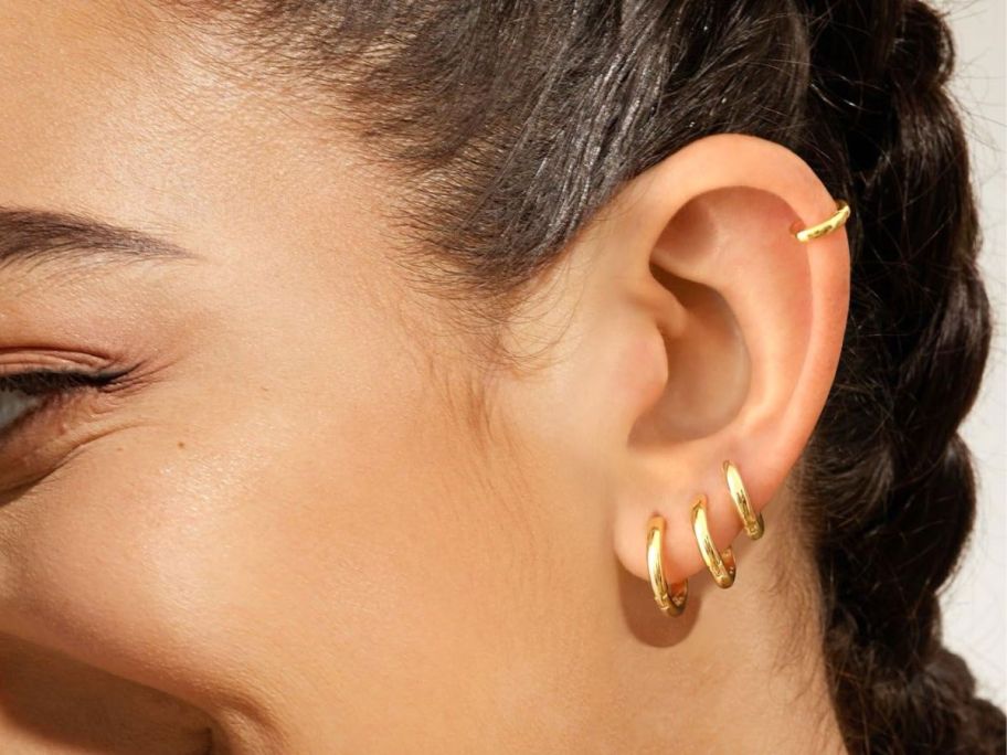 woman wearing 4 gold earrings in ear
