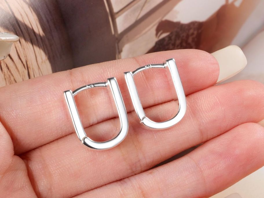 hold holding pair of silver earrings