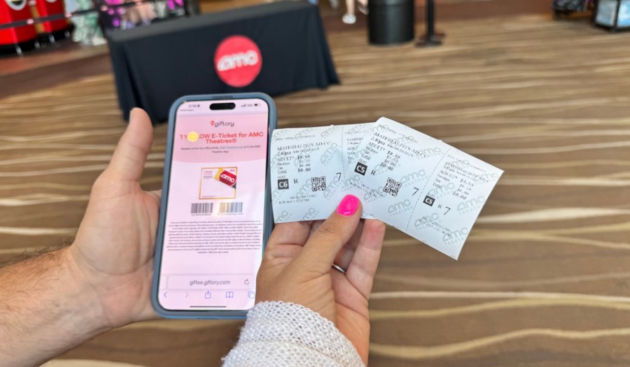 woman holding amc theater tickets near a phone