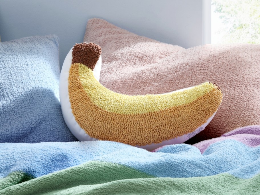 a yellow banana pillow on a bed with other pillows