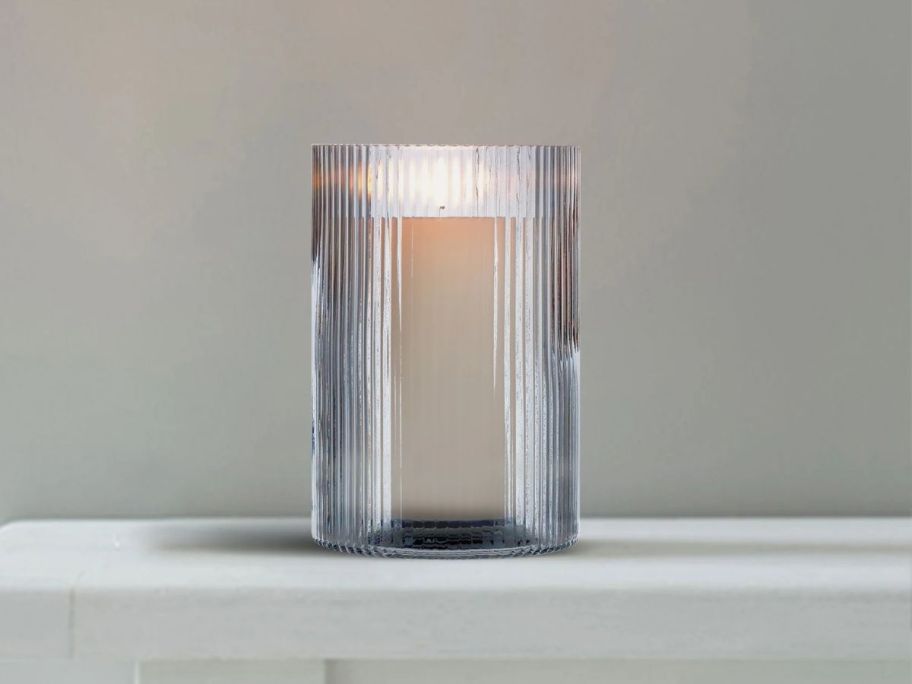 Better Homes & Gardens 8" Glass Ribbed Hurricane Candleholder on table with candle in it