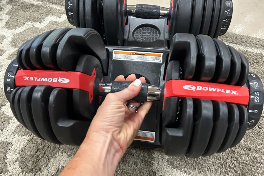 hand holding adjustable dumbbell