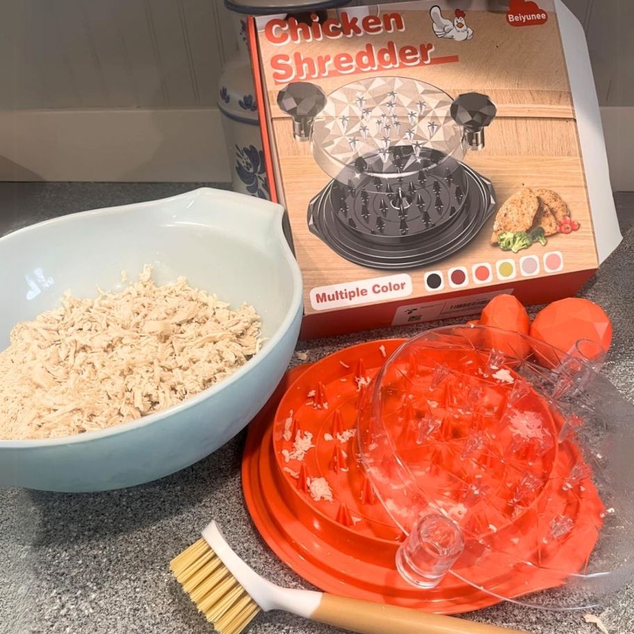 a chicken shredder whown with cleaning brush, a bowl of shredded chicken