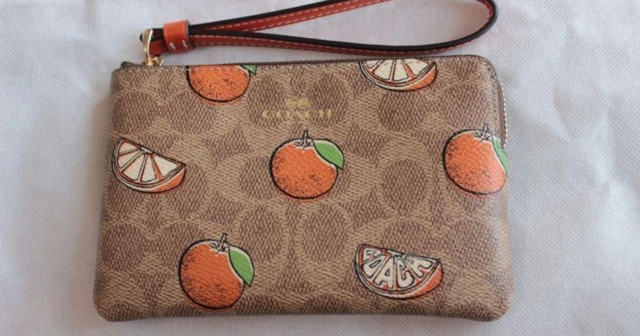 Coach Corner Zip Wristlet in Orange Print laying down