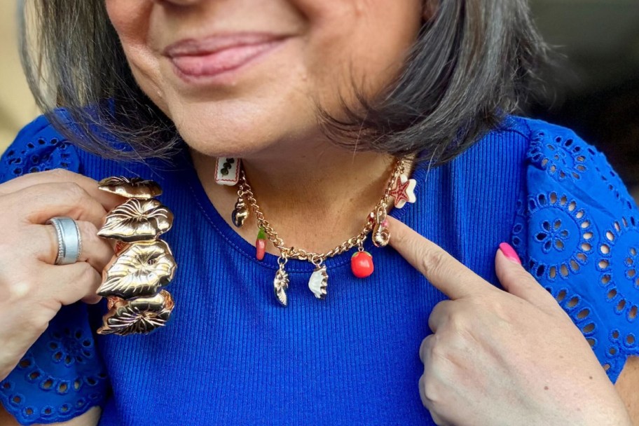 woman pointing at tomato and sardine gold charm necklace